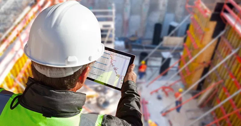 construction worker looking at construction software on tablet