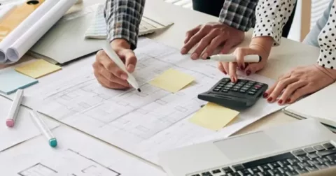 construction cost estimates symbolized by construction guys calculating on the table with construction drawings